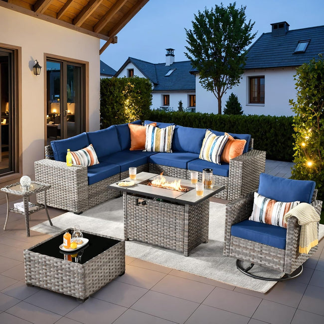 Outdoor patio set with blue sofa, chairs, and fire pit table on a patio.