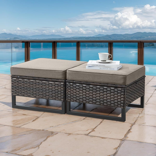 Wicker outdoor bench with cushions on a patio with a scenic view of water and mountains.