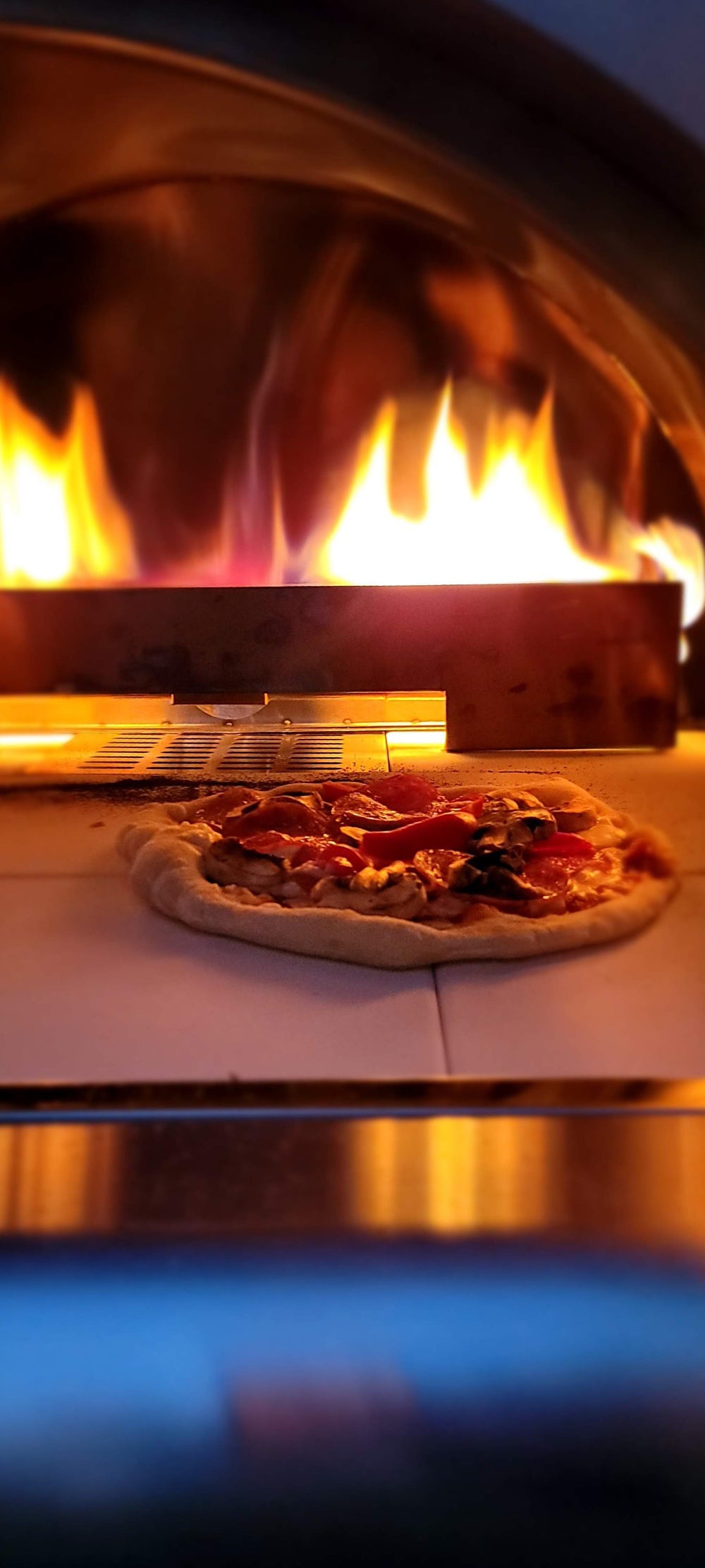 Pizza baking in a wood-fired oven with flames