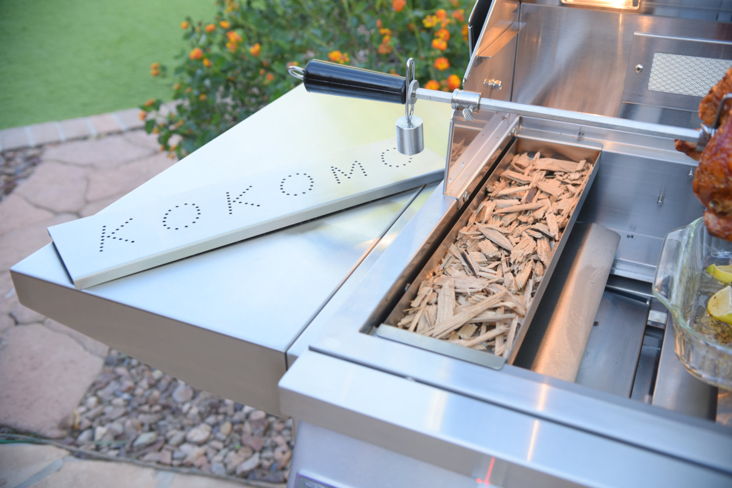 Outdoor grill with wood chips and 'Kokoma' branding on a patio