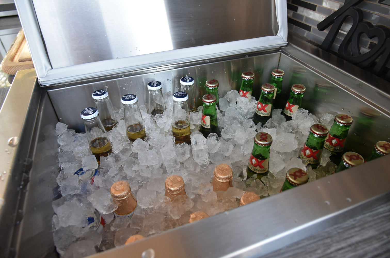 Bottles of beer and soft drinks on ice in a metal cooler.