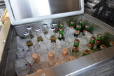 Bottles of beer and soft drinks on ice in a metal cooler.