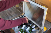 Person opening a cooler filled with bottles of wine.
