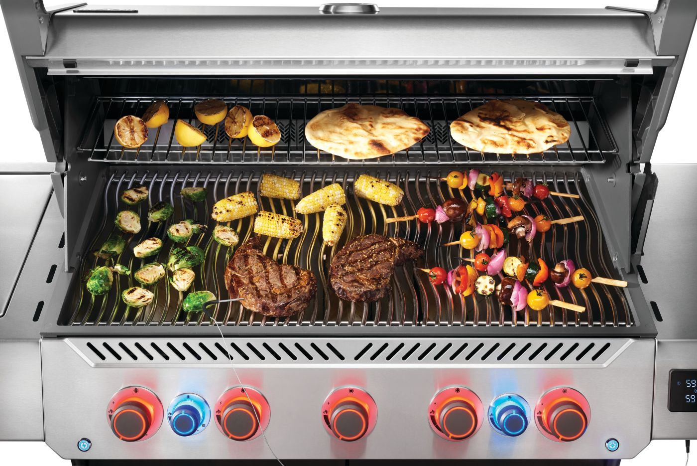 Stainless steel grill with various foods being cooked on different grates.
