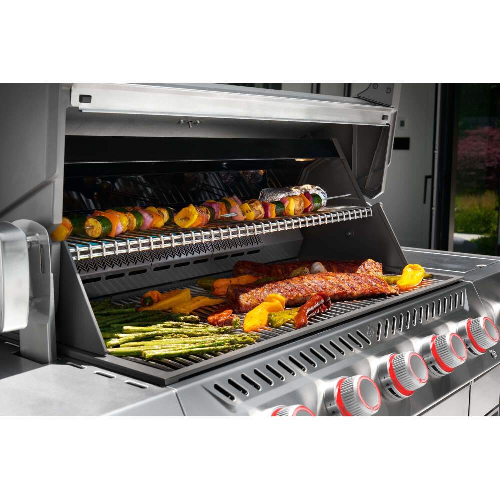 Grill with various foods being cooked, including vegetables and meats.