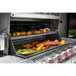 Grill with various foods being cooked, including vegetables and meats.