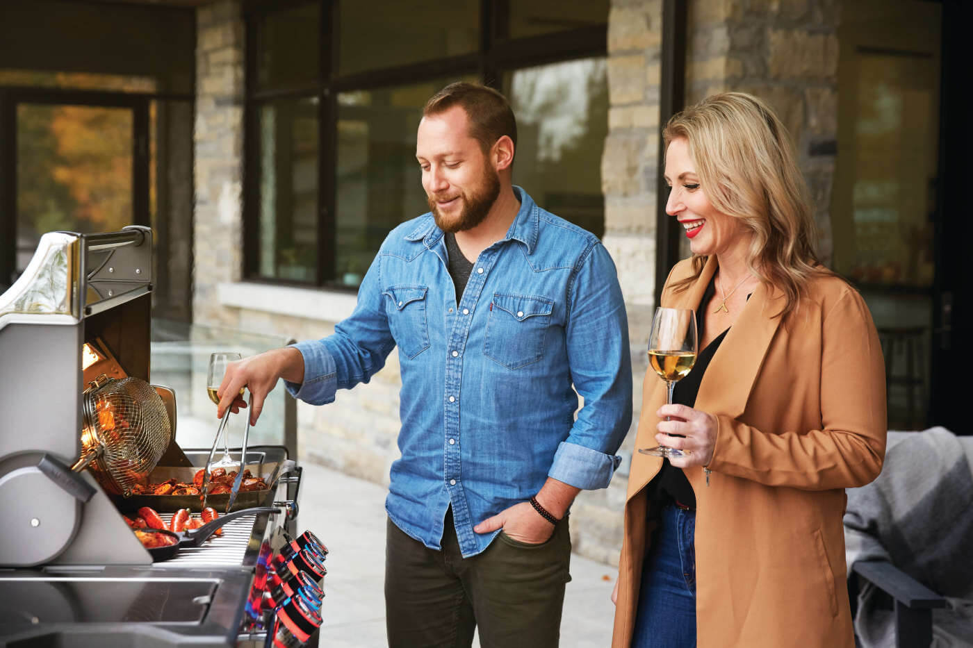 Man and woman grilling outdoors with a focus on the grill and their interaction.