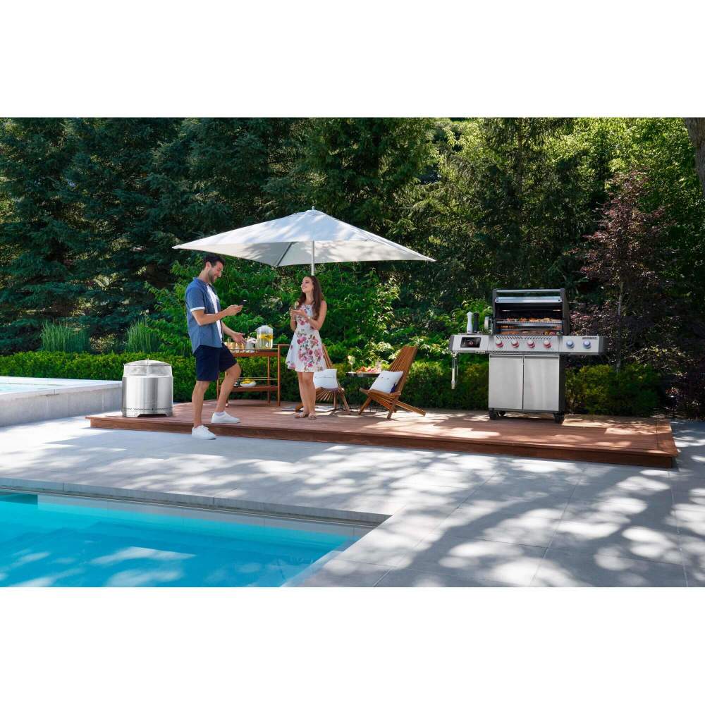 Two people by a poolside with a grill and umbrella