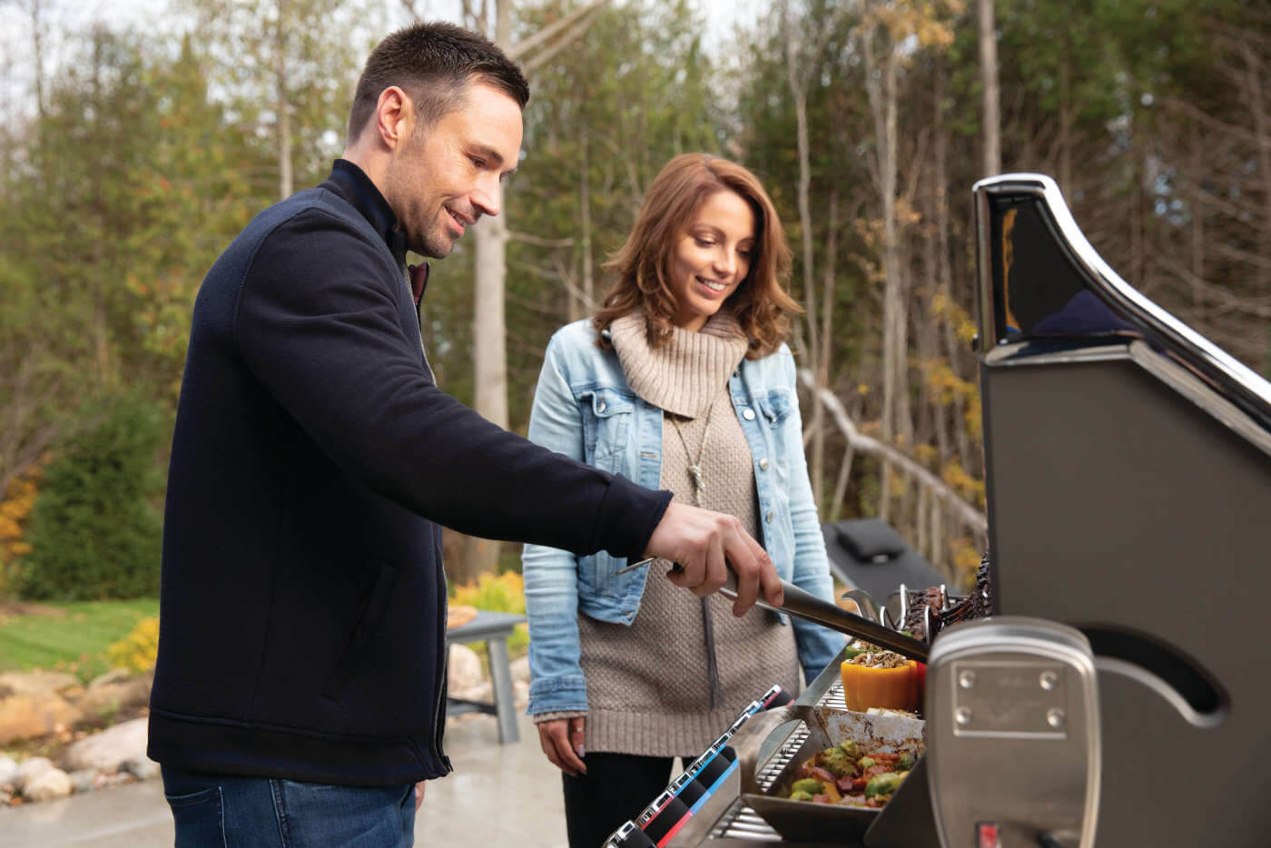 Man and woman grilling outdoors with a barbecue