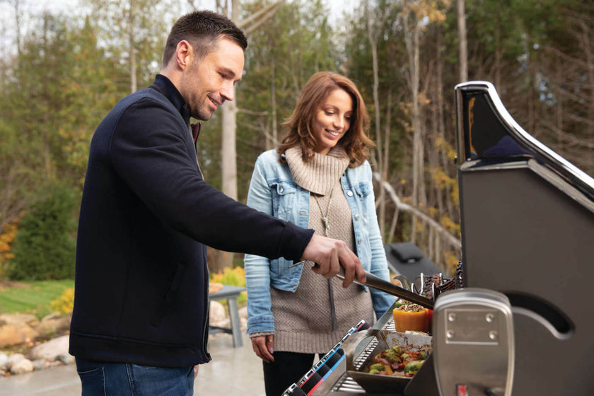 Man and woman grilling outdoors with a barbecue