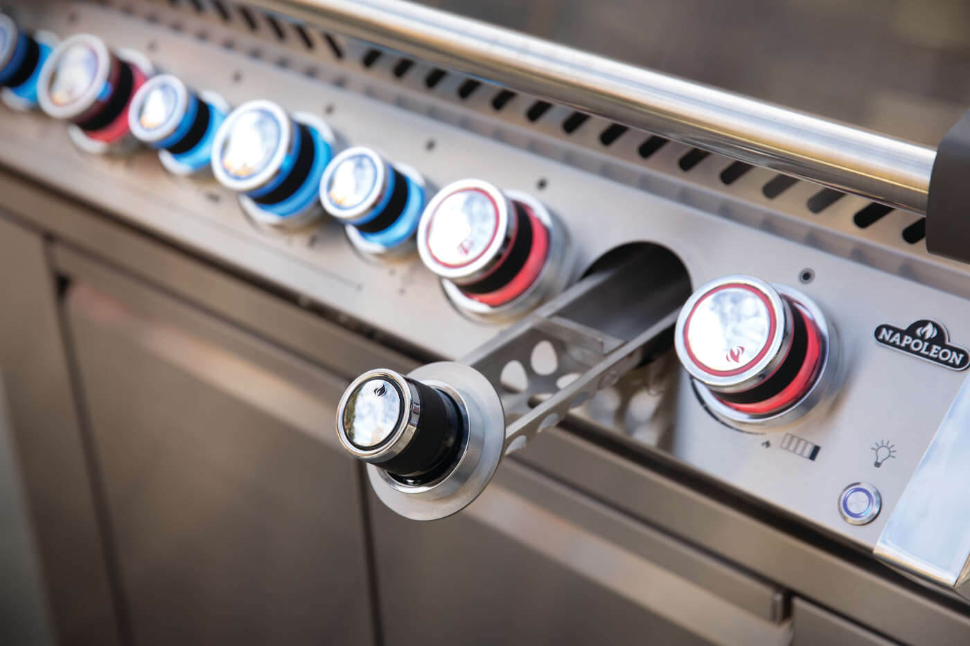 Control knobs on a stainless steel grill with a brand logo.