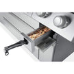 Stainless steel oven with a drawer open, showing wooden chips inside.