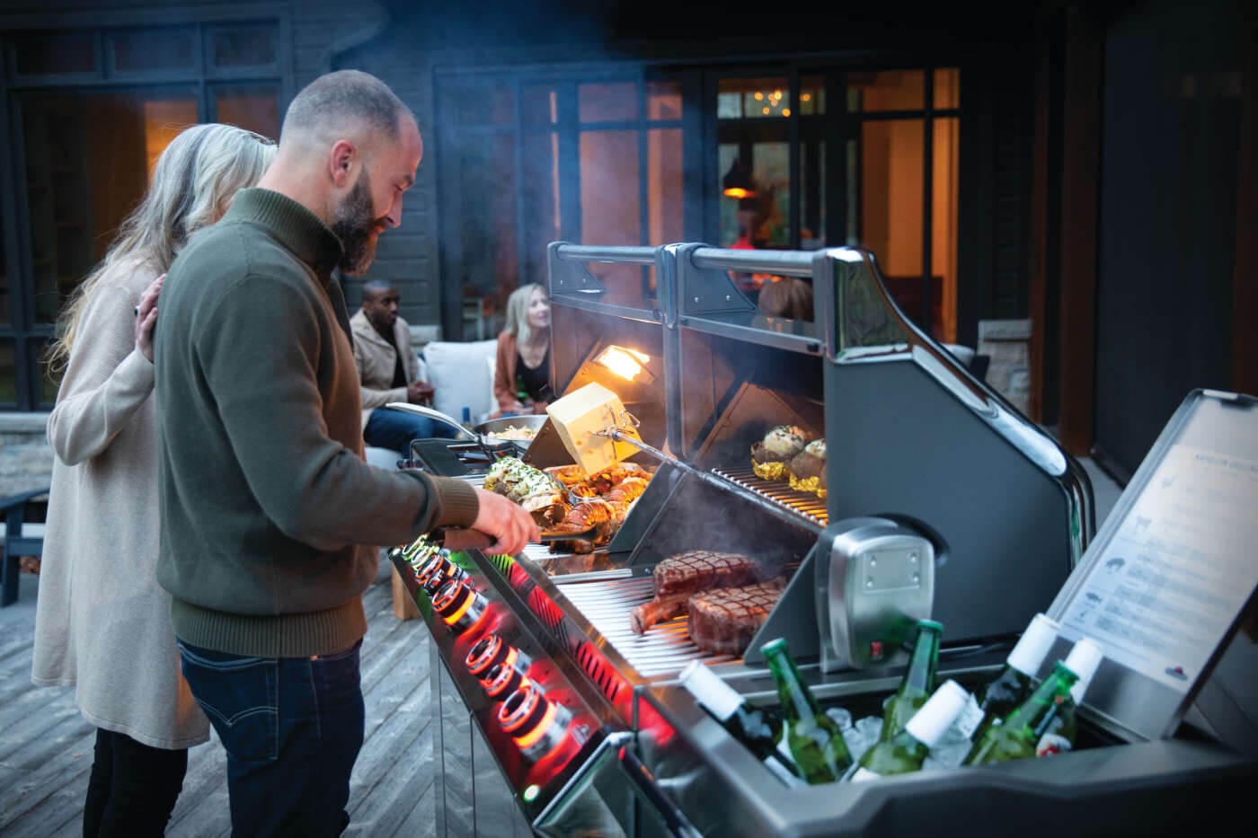 People grilling food on a barbecue grill outdoors at night.