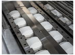 Row of white cylindrical objects on a metal conveyor belt