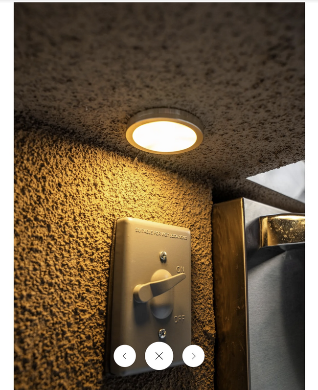 Ceiling light fixture on a textured ceiling with a light switch below.