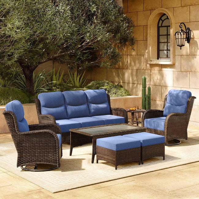 Outdoor patio furniture set with blue cushions in a garden setting.