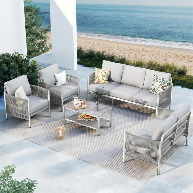 Outdoor patio set with gray sofa and chairs on a patio with ocean view
